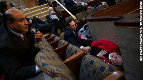 US Rep. Jason Crow comforts Rep. Susan Wild while taking cover as protesters disrupt the joint session of Congress to certify the Electoral College vote on January 6, 2021. 