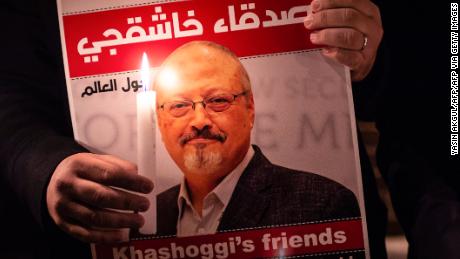 A demonstrator holds a poster picturing Saudi journalist Jamal Khashoggi and a candle during a gathering outside the Saudi Arabia consulate in Istanbul, on October 25, 2018. 