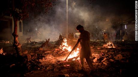 Workers can be seen at a crematorium where multiple funeral pyres are burning for people who lost their lives to Covid-19 on Thursday in New Delhi, India.