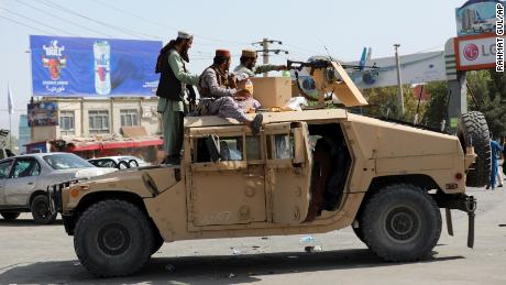 Taliban fighters stand guard in front of the Hamid Karzai International Airport, in Kabul, Afghanistan, Monday, Aug. 16, 2021. 