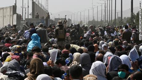 TOPSHOT - Afghans gather on a roadside near the military part of the airport in Kabul on August 20, 2021, hoping to flee from the country after the Taliban's military takeover of Afghanistan.