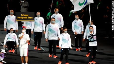 Karimi (right) led the Refugee Paralympic Team with fellow flagbearer Alia Issa (center left) in the parade of athletes during the Opening Ceremony of the Tokyo 2020 Paralympic Games.