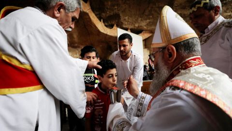 A boy receives communion from an Egyptian Coptic Orthodox Christian priest on April 17, during a Palm Sunday Mass in the Samaan el-Kharaz Monastery, in the Mokattam Mountain area of Cairo, Egypt.