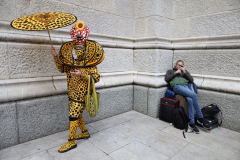 A costumed person stands next to a person waiting with bags during New York City's Easter Parade and Bonnet Festival on Sunday, April 17.